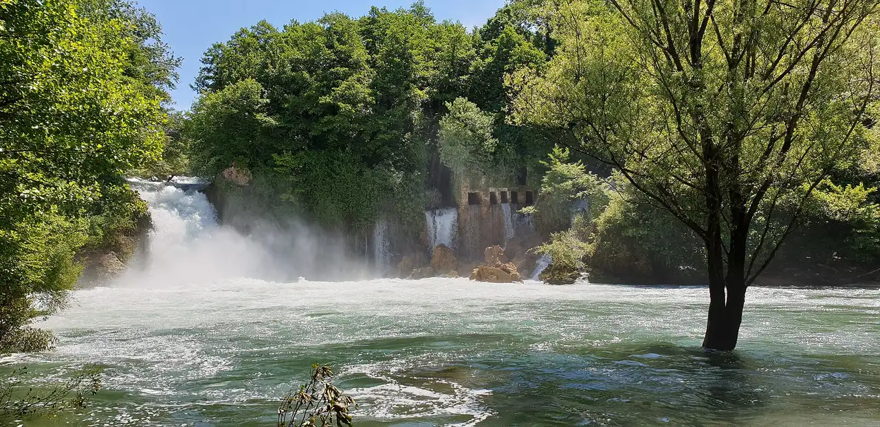 The wide low curtain of Bilušića buk fanning across the young Krka river below Knin