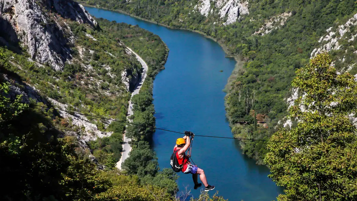 Zipline riders crossing high above the Cetina canyon near Omis