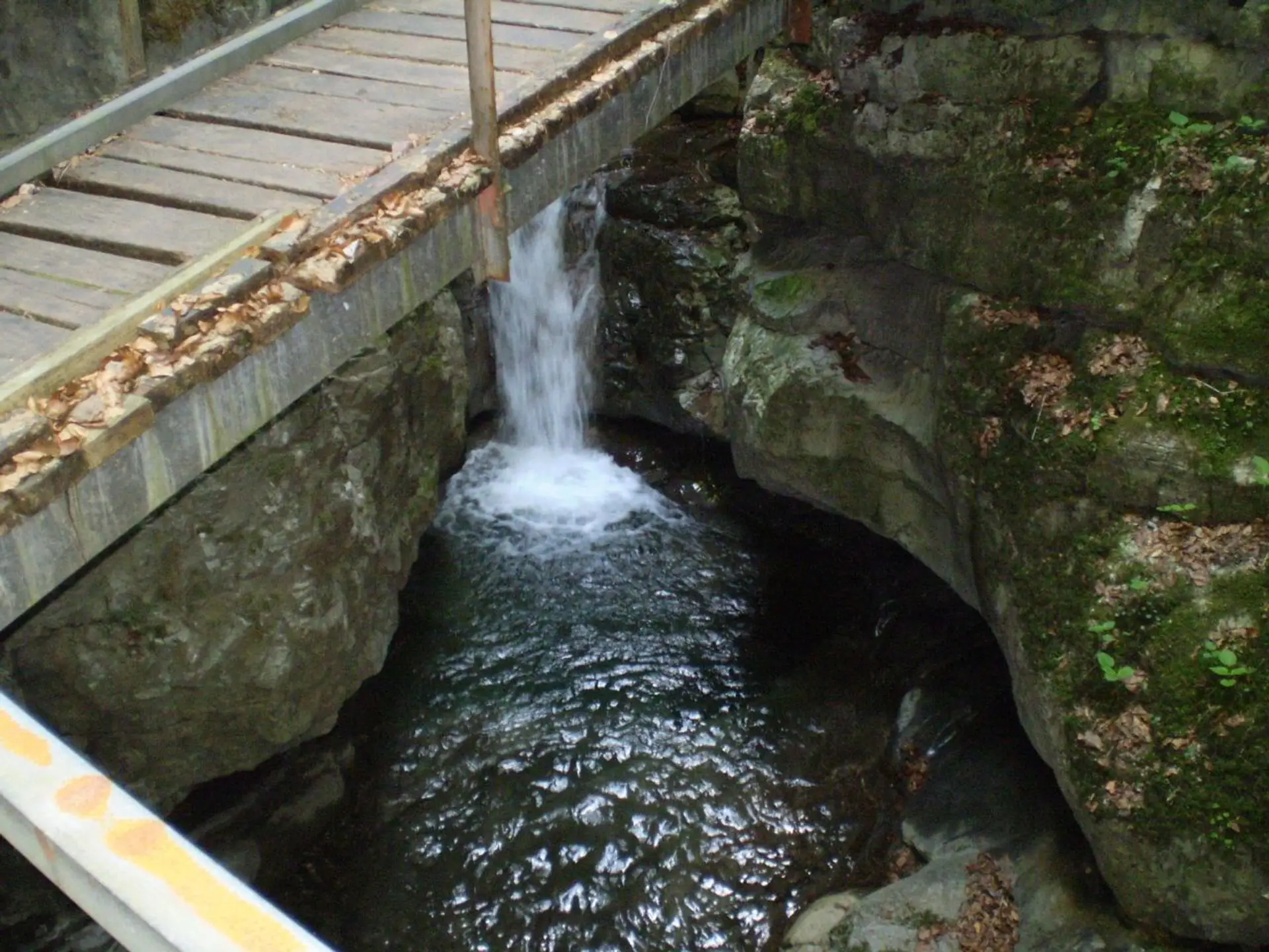 The fenced wooden walkway of the Gorski Kotar gorge clipped to the rock above green water